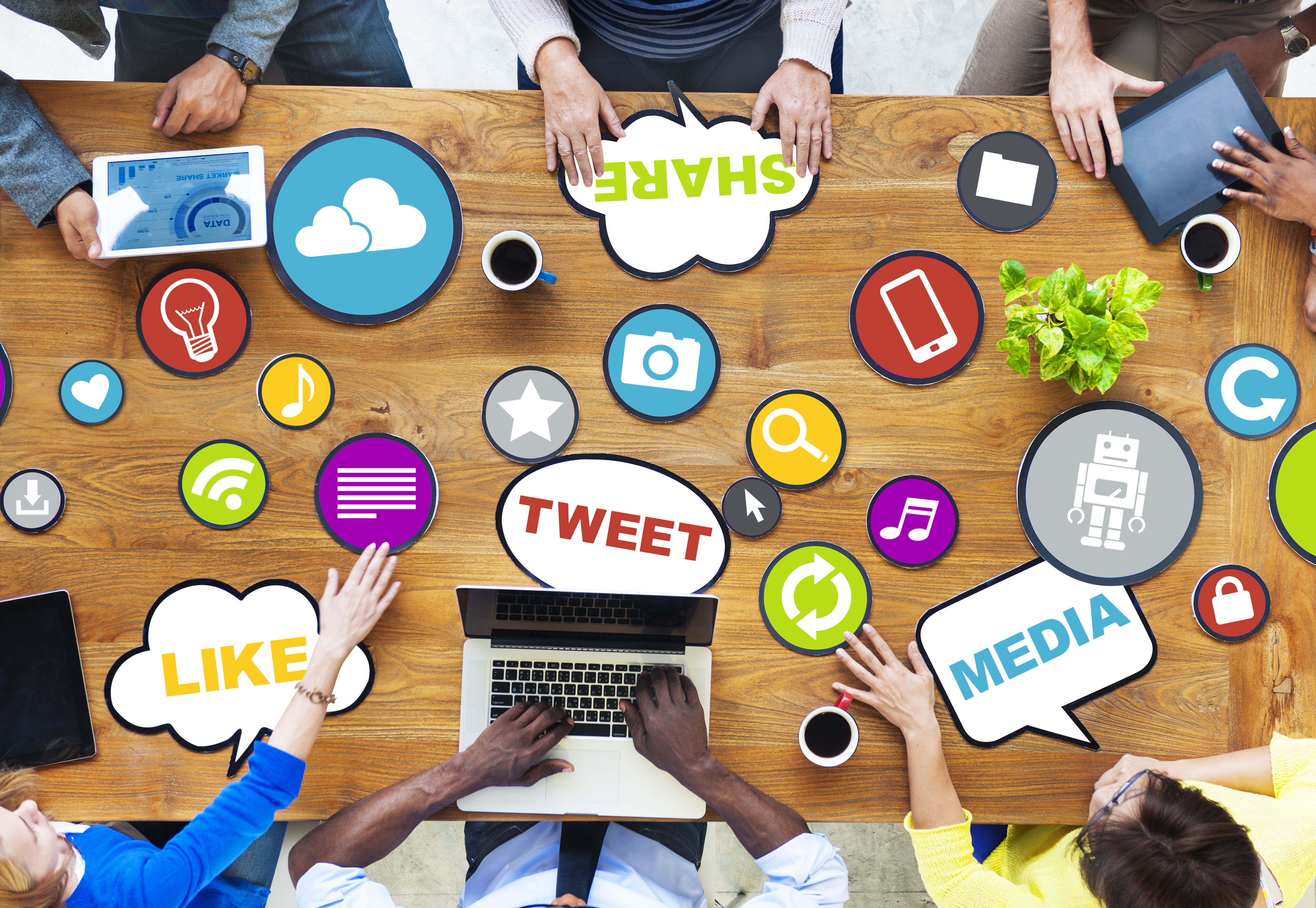 six colleagues meeting at a confrence table discussing social media marketing buzz words such as tweet, media, and like flying across the table